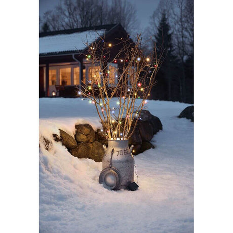 LED Lichterkette Timer 8 Funktionen und Memoryfunktion 128 bunte Dioden batteriebetrieb IP44 an einem winterlichen Außenbereich.
