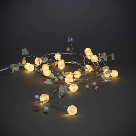 LED Lichterkette mit Dekoblättern 6h Timer batteriebetrieben auf dunklem Hintergrund.