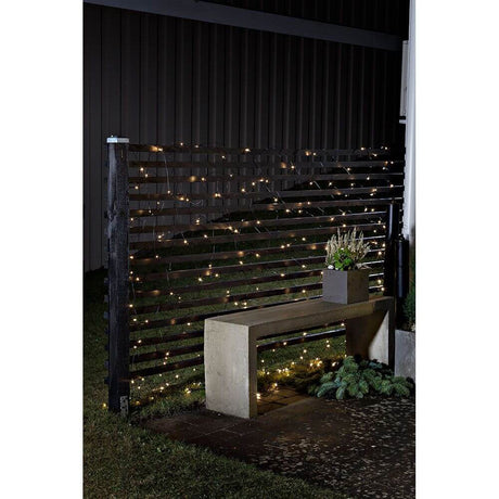 LED Lichternetz mit Timer und Multifunktion 240 Warmweiße Dioden batteriebetrieben IP44 an einem Zaun bei Nacht.