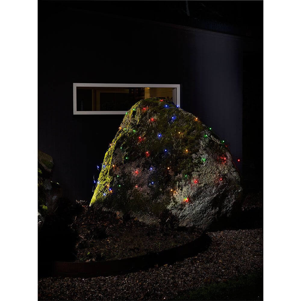 LED Lichternetz mit bunten Globes 80 bunte Dioden IP44 auf einem großen Stein im Garten bei Nacht.