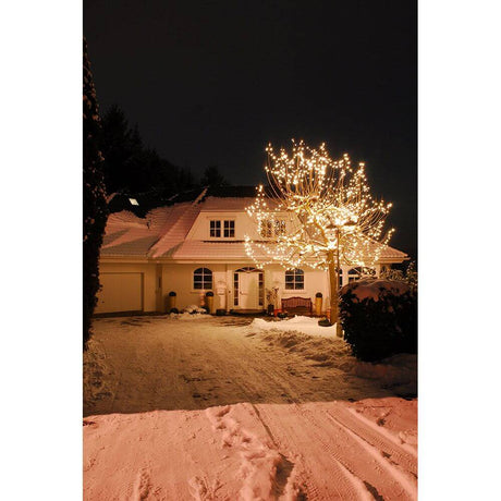 LED Minilichterkette 304 Warmweiße Dioden IP44 erhellt ein festlich geschmücktes Haus im Schnee bei Nacht.