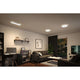 Modernes Wohnzimmer mit eckigem LED Panel Atria Shine in Schwarz und warmweißem Licht.