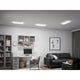 LED Panel Atria Shine Wärme-Dimmbar Weiß in modernem Wohnraum mit Schreibtisch und Sofa.