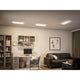 LED Panel Atria Shine Panel Eckig Weiß in modernem Wohnraum mit Schreibtisch und Couchtisch.