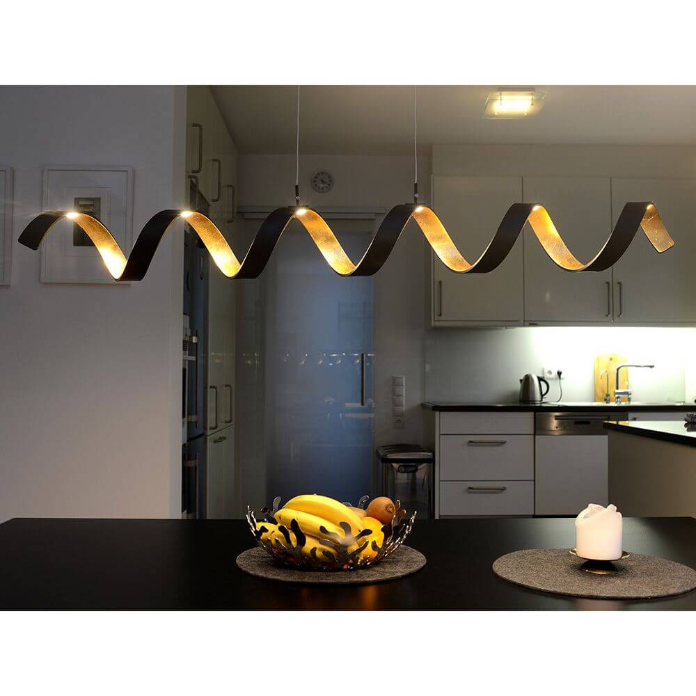 LED Pendelleuchte Helix Goldfarben, Schwarz über einem Esstisch in einer modernen Küche.