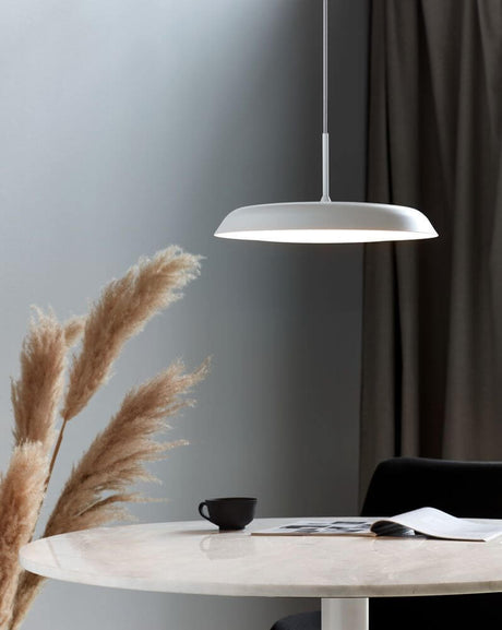 LED Piso pendant light with Scandinavian minimalism above a table with coffee and notes.