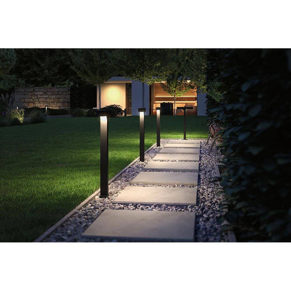 LED Pollerleuchte Dobla Anthrazit Aluminium beleuchtet einen Weg in einem Garten.