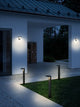Moderne LED Pollerleuchten Rica Square Solar IP44 beleuchten den Eingang bei Nacht in einem minimalistischen Garten.