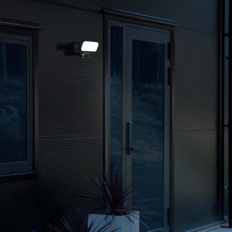 LED Smartlight Wandleuchte Kamera+Lautsprecher an einer Wand, beleuchtet einen Eingangsbereich bei Nacht.