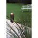 LED Sockellampe BU-OH 56cm IP65 Dunkelgrau im Garten auf Rasen und Pflastersteinen, umgeben von Grünpflanzen.