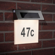 LED Solar Hausnummernleuchte IP44 Edelstahl, Weiß mit der Hausnummer 47c an einer Ziegelwand montiert.