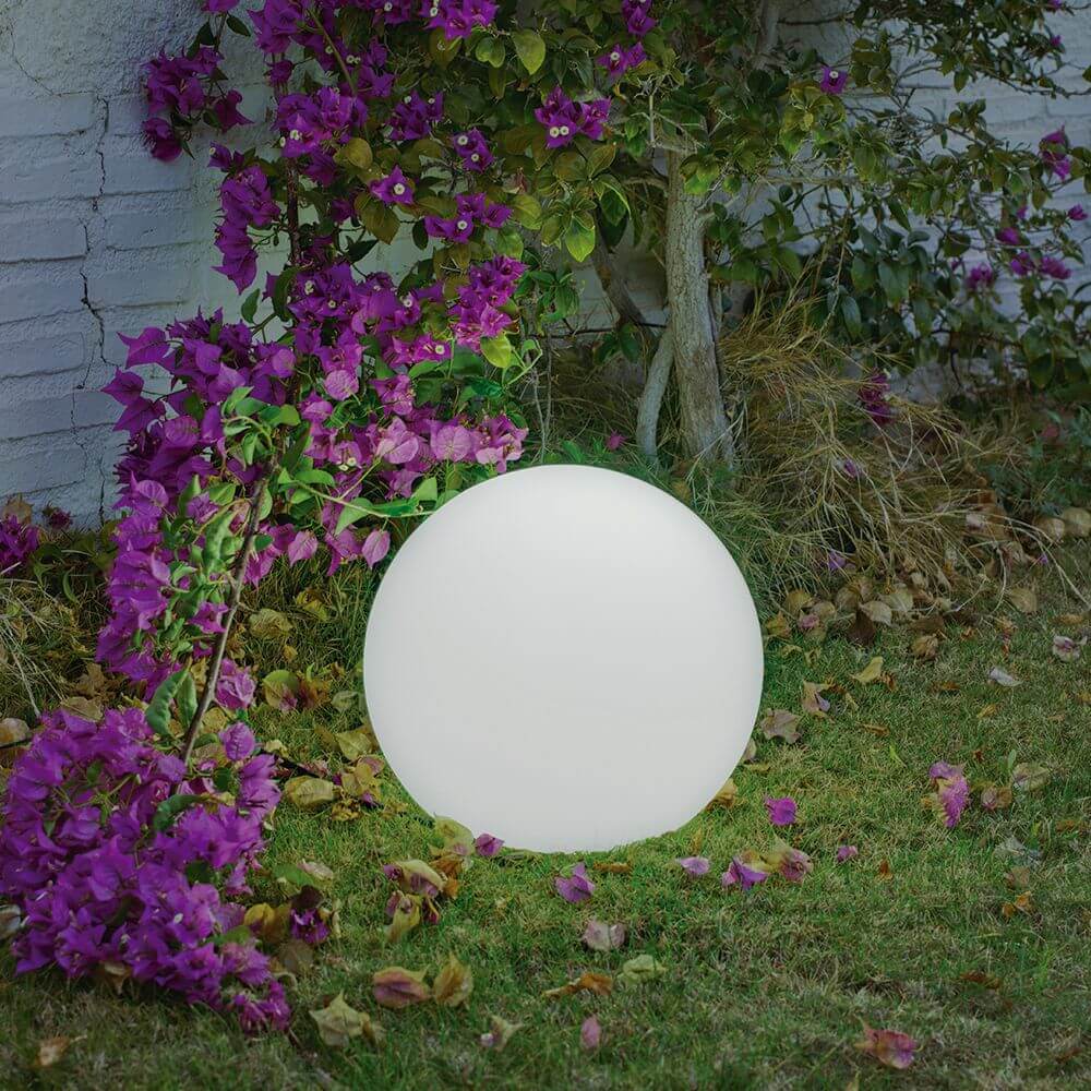 Lampe à boule solaire LED Buly Ø40cm IP65 avec batterie et télécommande dans le jardin entre des fleurs violettes.