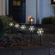 LED Spießleuchte mit 5 Schneeflocken Klar in einem dekorativen Gartenbeet bei Nacht.