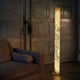 LED Stehleuchte Columna aus Stein Weißperle neben einem Sofa in einem industriellen Raum.
