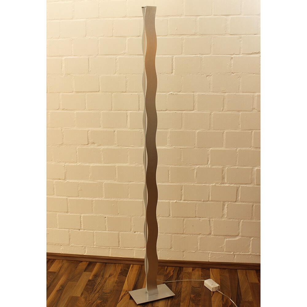 LED Stehleuchte Wave Dimmbar Nickel-Matt, Chrom auf Holzfußboden vor weißer Wand.