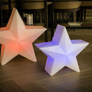 LED Stern Nova Akku + Solar IP65 étoiles lumineuses en rouge et bleu sur fond en bois.