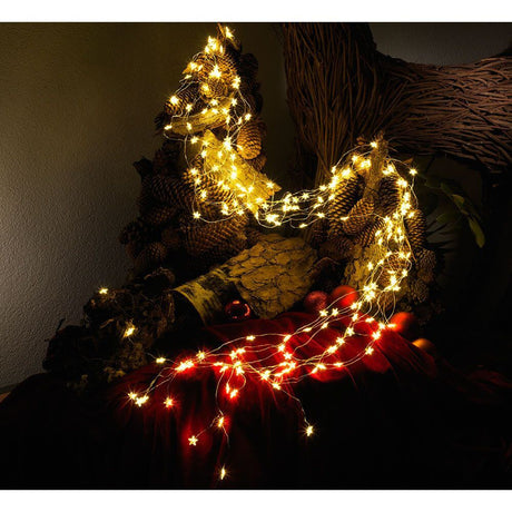 LED Sternenlametta 10 brins avec 20 diodes 200 diodes blanc chaud décorativement autour d’une composition rustique de cônes de pin.