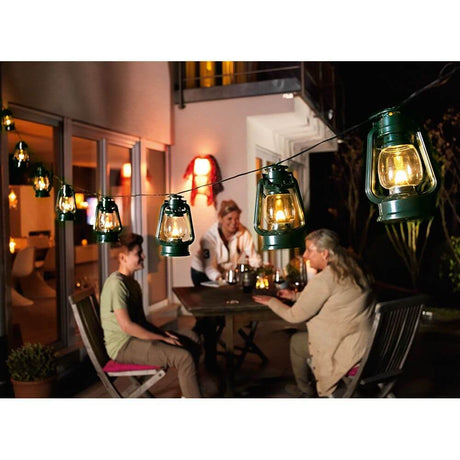 LED Sturmlaternen Lichterkette 8 grüne Sturmlaternen 8 Warmweiße Dioden IP44 auf Terrasse mit Menschen bei Nacht.