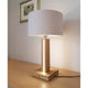 LED Tischlampe Asseto 980lm Eiche-Geölt, Beige auf einem Holztisch mit grauem Lampenschirm und sanftem Licht.
