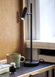 LED Tischlampe Omari auf einem Schreibtisch mit einer Tasse und einem Notizbuch.