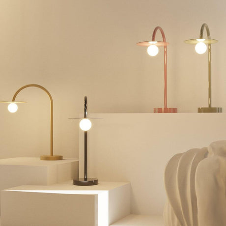 LED Tischleuchte Enigma 3000K in Schwarz, Rot, Gold und Grün auf Stufen, modernes Design und vielfältige Farboptionen.