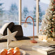 Moderne LED Tischleuchte Enigma 3000K auf einem Tisch, umgeben von weihnachtlicher Dekoration.