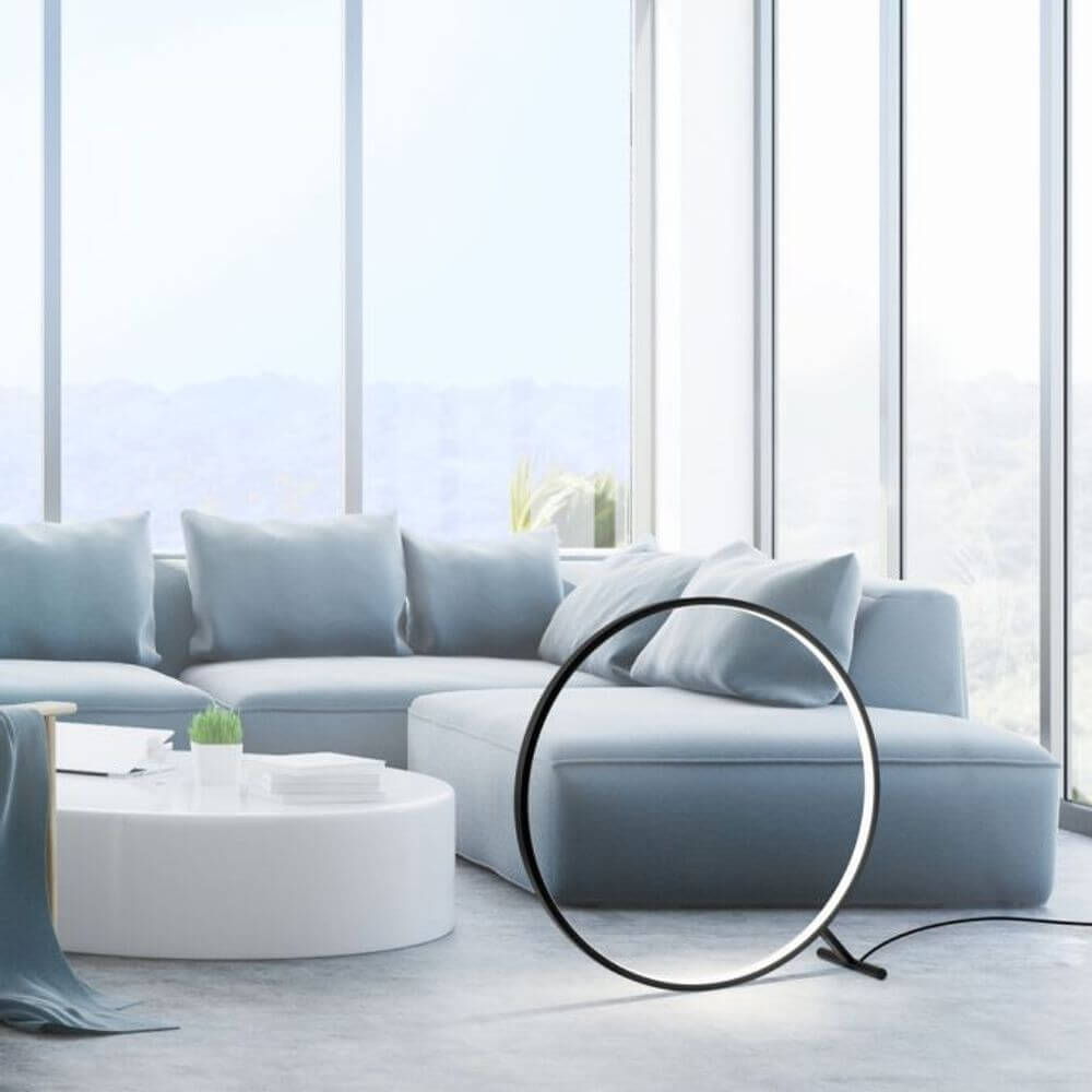 LED Tischleuchte Hula mit Fernbedienung in modernem Wohnambiente mit Sofa und großem Fenster.