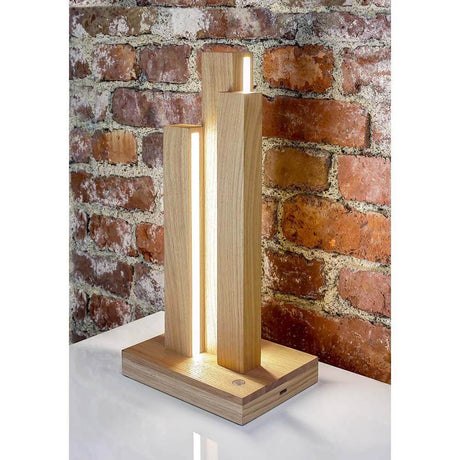 LED Tischleuchte Manhattan Touch-Dimmer 910lm Eiche-Geölt auf einem Tisch vor einer Backsteinmauer.