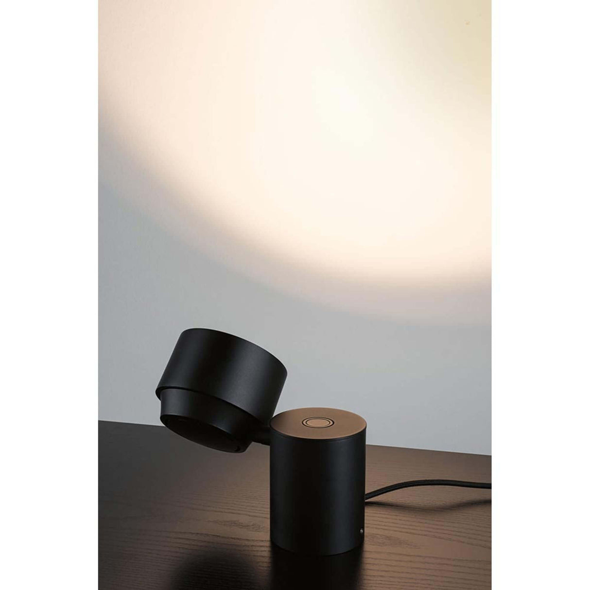LED Wand- & Tischleuchte Puric Pane mit Touch-Dimmer Schwarz auf einem Tisch mit sanfter Lichtprojektion