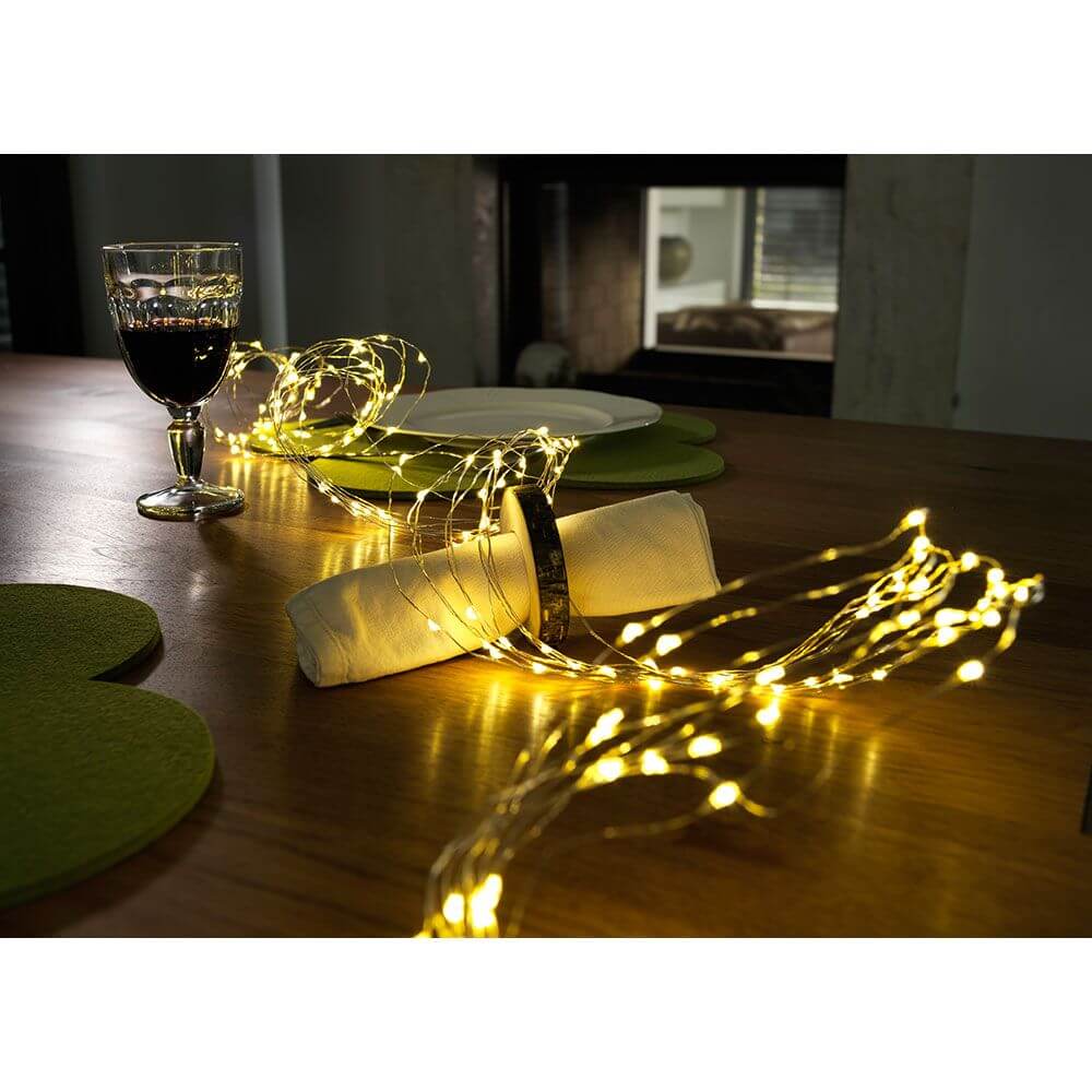 LED Tropfenlametta 10 Stränge mit 20 Dioden 200 Warmweiße Dioden auf einem Tisch mit Rotwein und Serviette.