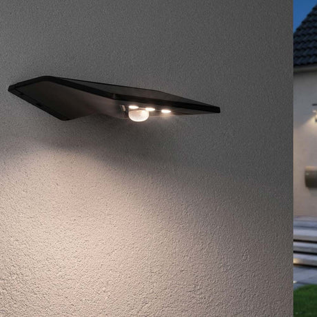 LED Wand-Solarleuchte Yoko mit Sensor IP44 3000K Anthrazit an einer Wand montiert, mit leuchtender Orientierungsbeleuchtung.