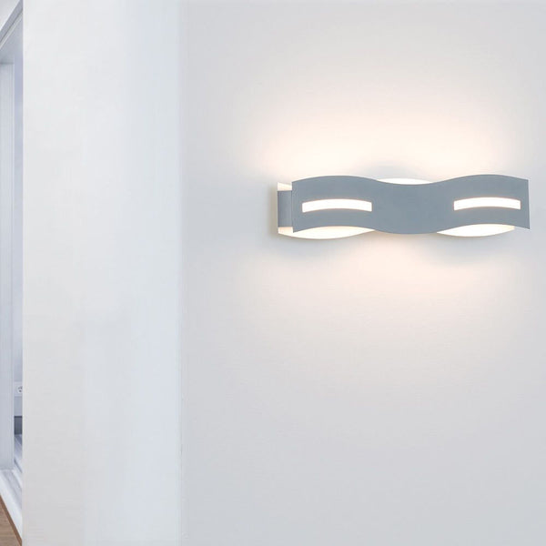 LED Wandlampe Wave Nickel-Matt, Chrom an einer Wand montiert, strahlt warmweißes Licht aus.