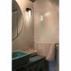 LED-vegglampe BRUME 3W 2700K IP44 bronse i moderne bad med rund speilbelysning.