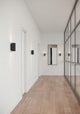 LED Wandleuchte Curtiz in modernem Flur mit Holzfußboden und Spiegelwand.