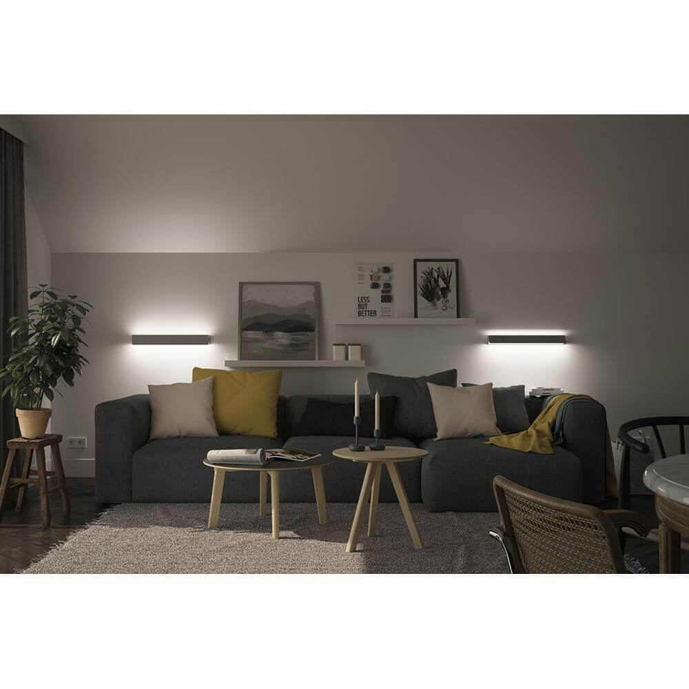 LED Wandleuchte Katla Metall 60cm an einer gemütlichen Wohnzimmerwand, strahlt indirektes Licht aus.