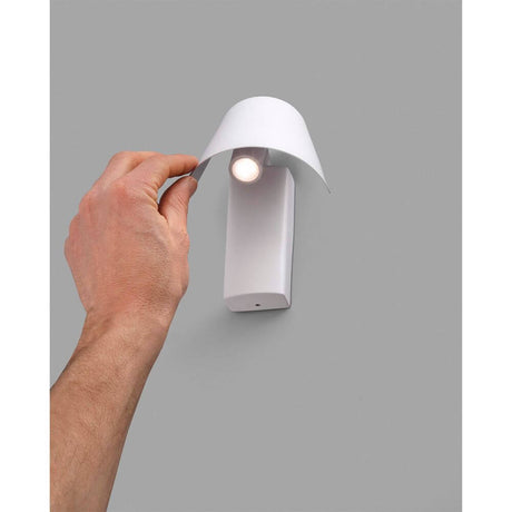 LED Wandleuchte LE PETIT Weiß mit Hand, die Abdeckung anhebt, auf grauem Hintergrund.