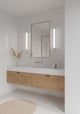 LED Wandleuchte Malaika 68 IP44 neben dem Badezimmerspiegel mit Holzbadmöbeln und Pflanzen.