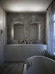 LED Wandleuchte Otis 40 IP44 installiert in modernem Badezimmer mit zwei Spiegeln.