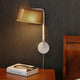 LED Wandleuchte Owalo 7030 aus Holz 47cm an einer Wand über einem Nachttisch mit einem Buch.