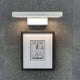 LED Wandleuchte Smal Touch-Dimmer 490lm Weiß über einem gerahmten Kunstwerk an einer Betonwand.