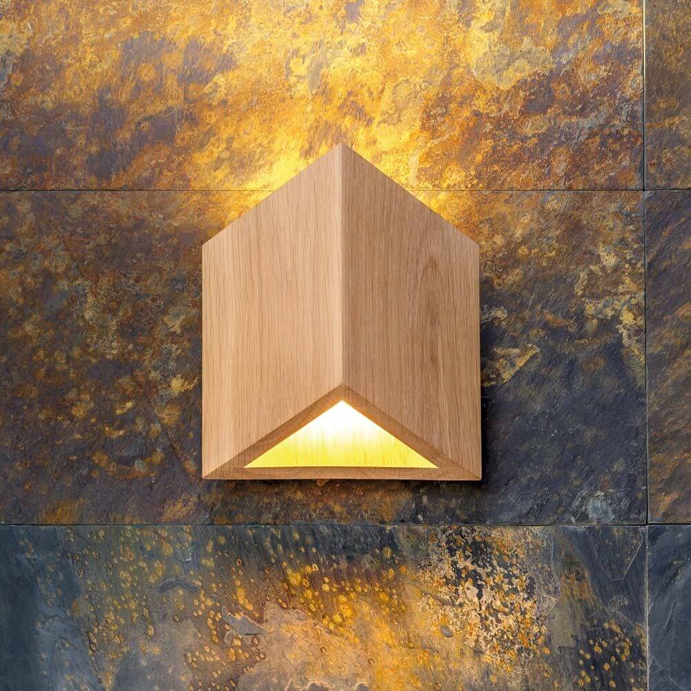 LED Wandleuchte Trekant 720lm Eiche-Geölt an einer Wand mit dekorativem Steinmuster.