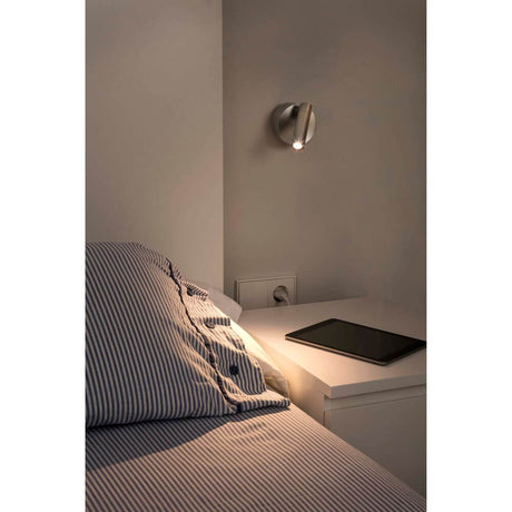 LED Wandstrahler BOC 3W 3000K Nickel-Satin montiert über einem Nachttisch mit einem Tablet.