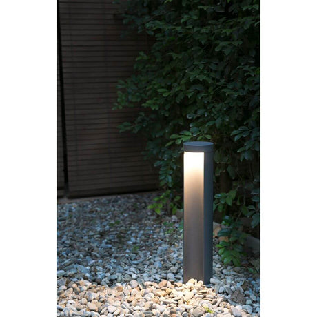 LED Lampe de chemin CHANDRA 7W 3000K IP54 gris foncé sur un chemin de gravier dans le jardin.
