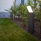 LED-Wegeleuchte Pano Lichtfarbe regelbar in einem Garten mit bepflanzten Beeten und Rasen.