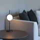Le Vita LED Tischlampe Touch-Dimmer Schwarz auf einem Tisch neben einem Sofa mit Kissen.