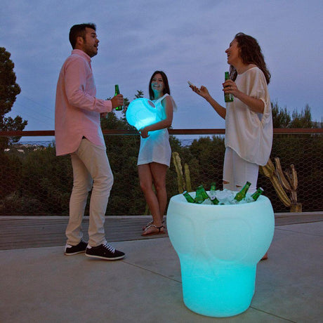 LED-arrefecedor de garrafas Melvin caveira com bateria, num ambiente animado com bebidas iluminadas.
