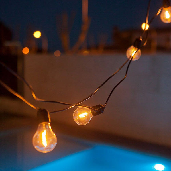 LED-Allegra garland 10-light black shines at night above a pool.