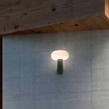 Applique murale Pepita LED Solaire + capteur sur un mur gris, crée une lumière chaude dans un design moderne.