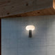 Pepita LED Wandleuchte Solar + Sensor an einer grauen Wand, erzeugt warmes Licht im modernen Design.