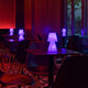 Lola LED-Außen-Tischleuchte Small in einem modernen Café mit bunten Lichtern und eleganten Tischen.